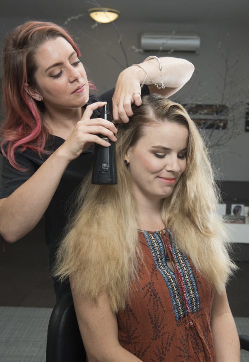 DAVID LIPNOWSKI / WINNIPEG FREE PRESS  Britney Robson uses Oribe products to tame frizzy and sun dried hair on model Raechel Warde at Edward Carrier salon Thursday July 21, 2016.