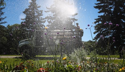 MIKE DEAL / WINNIPEG FREE PRESS  Ryan Bork with the City of Winnipeg waters the flowers at St. Vital Park Monday afternoon.   160725 Monday, July 25, 2016