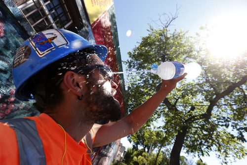JOHN WOODS / WINNIPEG FREE PRESS Claudio Vieira, concrete worker, cools down with some water as he works on some new sidewalks going in on Ellice and Maryland Monday, July 25, 2016. Temperatures are going to be high all week.