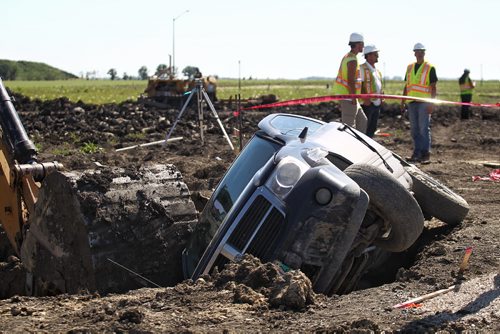 MIKE DEAL / WINNIPEG FREE PRESS  A van sits on its side in a hole being dug by a construction crew on Landover Drive in the new housing neighbourhood of Bridgewater in Winnipeg's south end Monday afternoon. A man was taken away by ambulance. No report on his condition was made available at the scene.   160725 Monday, July 25, 2016