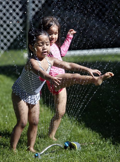 WAYNE GLOWACKI / WINNIPEG FREE PRESS  Five year old Azrielle,left, was visiting her neighbour Riley,3, whose mother had the pool and sprinkler in their front yard on Atlantic Ave. ready for the children to cool off Monday afternoon.    For  Weather story  July 25 2016