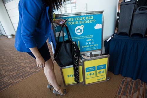 MIKE DEAL / WINNIPEG FREE PRESS A television reporter checks to see if her purse would qualify as a free personal bag at a testing display by the boarding gate for Newleaf Travel. 160725 - Monday, July 25, 2016