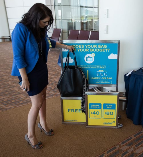 MIKE DEAL / WINNIPEG FREE PRESS A television reporter checks to see if her purse would qualify as a free personal bag at a testing display by the boarding gate for Newleaf Travel. 160725 - Monday, July 25, 2016