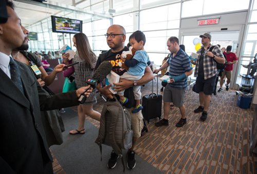 MIKE DEAL / WINNIPEG FREE PRESS Media interview the first passengers of first plane to arrive at the Winnipeg Richardson International Airport for Newleaf Travel after they exit the plane. 160725 - Monday, July 25, 2016