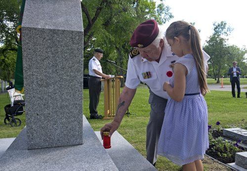 ZACHARY PRONG / WINNIPEG FREE PRESS  Dennis Lafreniere, a veteran of the Korean War who served with the Princess Patricia's Canadian Light Infantry (PPCLI), lays a candle with his granddaughter Violet Sigeti during a candlelight service at the Korean Veterans Cairn in the Field of Honour at Brookside Cemetery. Veterans, families, representatives of the Korean community and others gathered their to pay their respects to those who lost their lives in the conflict. July 27, 2016.