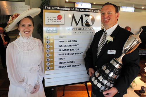 BORIS MINKEVICH / WINNIPEG FREE PRESS Derby Belle Paxton Oliver-Bingham and Assiniboia Downs CEO Darren Dunn pose for a photo with the draw board of the horses in the Manitoba Derby. Dunn holds the coveted prize for the winner. The event was at the downs on the second floor. July 28, 2016