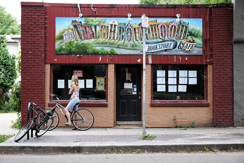 MIKE DEAL / WINNIPEG FREE PRESS  A cyclist reads the notice taped to the window of The Neighbourhood Cafe outlining the reason it is closed. The owner, Bill Fugler, is embroiled in a bylaw dispute with the city over installing a grease trap in his cafe.   160801 Monday, August 01, 2016