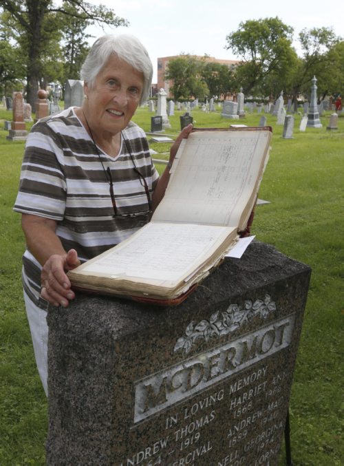 WAYNE GLOWACKI / WINNIPEG FREE PRESS  Margaret Steele gave the tour of the St. James Anglican Church cemetery across from Polo Park on Portage Avenue. She is with the original book of the cemetery's records at the grave stone of the McDermot family.   Kevin Rollason  story  August 03 2016
