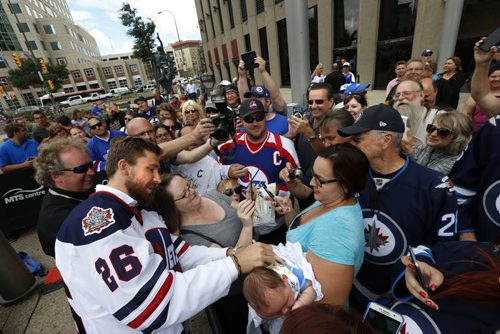 WAYNE GLOWACKI / WINNIPEG FREE PRESS   At the intersection of Portage and Main, Winnipeg Jets player Blake Wheeler at left wearing the Heritage Classic jersey at the NHL event Friday signs three month Aiden's shirt while being held by his mother Samantha Harris. Tim Campbell story August 5 2016