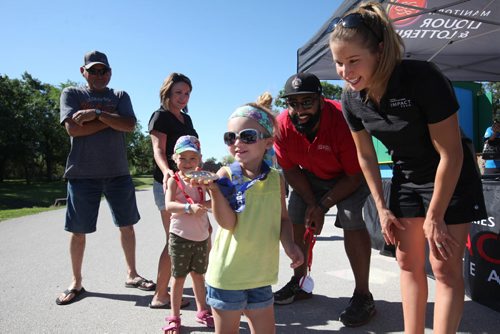 RUTH BONNEVILLE / WINNIPEG FREE PRESS  ZOOOLMYPICS - (standup pix)   Kaitlyn Lawes, Olympic Gold Medallist, Curling, lets 3-year-old Emerson Anderson check out her official gold medal that she won with her teammates in 2014 Olympics in Sochi at the impact tent with former CFL Football players Obby Khan Saturday.   Each station at the Assiniboine Park Zoo is set up to encourage visitors of all ages to get active like the athletes in Rio in  Activity Circuits which involve fun activities like climbing inflatables and races.   Aug 06, 2016