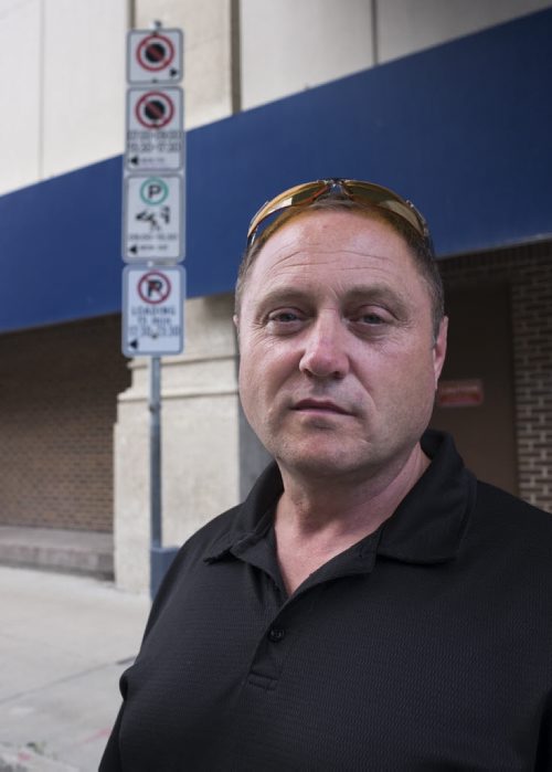 ZACHARY PRONG / WINNIPEG FREE PRESS  Todd Dube of Wise Up Winnipeg, a group that believes the city's traffic ticketing system is unfair and corrupt, in front of parking signs on Donald St. Dube says the signs or unnecessarily confusing and leave too many unsuspecting Winnipegers with hefty fines. August 6, 2016.