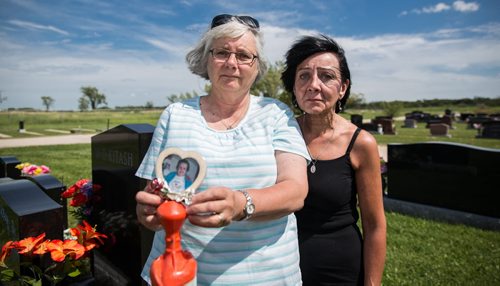 MIKE DEAL / WINNIPEG FREE PRESS Sisters, June Feakes (left) holding a photo of their mother and Brenda Winning Jensen (right) at the plot site of their mother Nellie Yosyk who died in February and whose pre-paid tombstone is nowhere to be found. 160808 - Monday, August 08, 2016