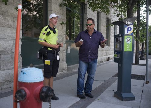 ZACHARY PRONG / WINNIPEG FREE PRESS  Russ Shewchuk argues with a parking enforcement officer who asked not to be named shortly after he parked his car on Market Ave. Despite signs saying paid parking is allowed in this location the officer told Shewchuk he would receive a ticket if he did not move. The officer said he understands the signs are incorrect but that he is still required to give tickets to anyone parked here. August 8, 2016.