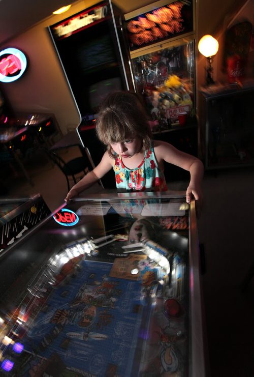 PHIL HOSSACK / WINNIPEG FREE PRESS - 7 yr old Jillian Swanson focuses on a pinball machine in her parent's basement near Selkirk. Eric and Angela Swanson have been collecting pinball machines and arcade memoribilia for years. See Dave Sanderson story. August 8, 2016