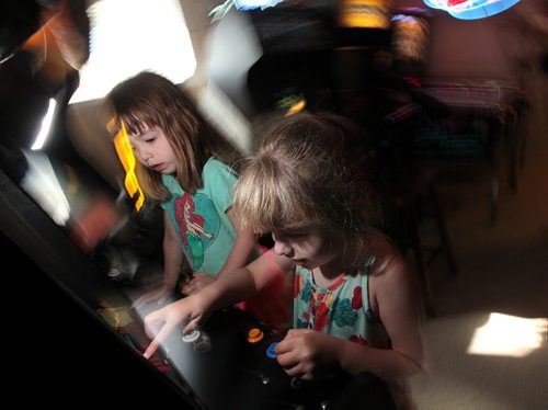 PHIL HOSSACK / WINNIPEG FREE PRESS - 4 yr old Amy (left) and her sister 7 yr old Jillian Swanson focus a video game  machine in her parent's basement near Selkirk. Eric and Angela Swanson have been collecting pinball machines and arcade memoribilia for years. See Dave Sanderson story. August 8, 2016
