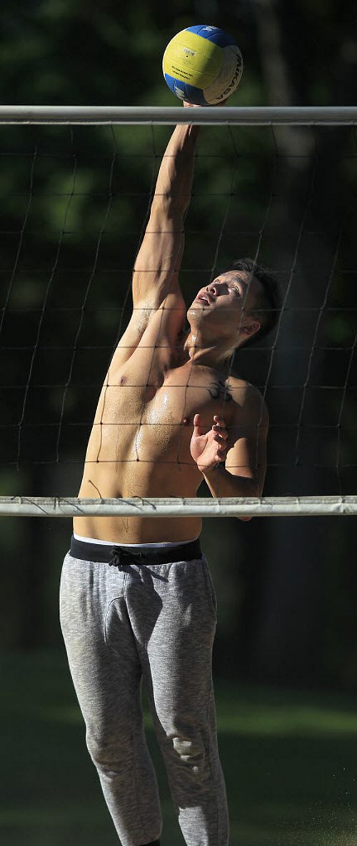 PHIL HOSSACK / WINNIPEG FREE PRESS -  STAND-UP - SHADOW and LIGHT - Keith Fernandez reaches high for a spike while playing a little beach volleyball at Assinaboine Park Wednesday evening.  Temps were forcast for highs of 23C Wed but soared over 27C late in the afternoon. The next coupe of days are cool and wet.  August 10, 2016