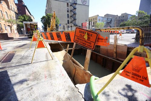 TREVOR HAGAN / WINNIPEG FREE PRESS A crew examines a large hole full of water on King Street north of Notre Dame, Tuesday, August 16, 2016. King is close to McDermot Avenue.