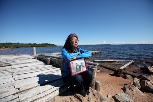 RUTH BONNEVILLE  / WINNIPEG FREE PRESS  Nancy Powderhorn sits on the shores of Tadoule Lake Tuesday holding a picture of her when she was a young girl in Duck Lake where she lived before the forced relocation of the Dene people to a community near Churchill.  Minister Carolyn Bennett made a formal apology to the Dene People in Tadoule Lake Tuesday which includes financial settlement.  See Alex Paul story.    Aug 16 / 2016