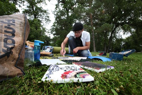 RUTH BONNEVILLE  / WINNIPEG FREE PRESS  Jurek Wielkopolan takes a break from his usual job to have a painting picnic, as he calls it, with acrylic and chalk in Crescent Park Thursday morning.  He was finishing a piece he started while listening to the music at Interstellar Rodeo on the weekend while painting on the grass with his daughter.   Standup photo Aug 17 / 2016