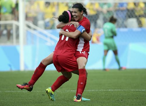 2016 Rio Olympics - Soccer - Final - Women's Football Tournament Bronze Medal Match - Brazil v Canada - Corinthians Arena - Sao Paulo, Brazil - 19/08/2016. Christine Sinclair (CAN) of Canada and Desiree Scott (CAN) of Canada celebrate winning the match as Barbara (BRA) of Brazil walks away. REUTERS/Paulo Whitaker TPX IMAGES OF THE DAY. FOR EDITORIAL USE ONLY. NOT FOR SALE FOR MARKETING OR ADVERTISING CAMPAIGNS.   - RTX2M41Q
