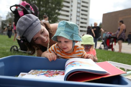 RUTH BONNEVILLE  / WINNIPEG FREE PRESS  One-year-old Simon Wiebe browses through books provided by The Very Read-y Project with his mom Lisa at the 7th Annual North End Family Centre BBQ at Champlain School Saturday.    Aug 19 / 2016