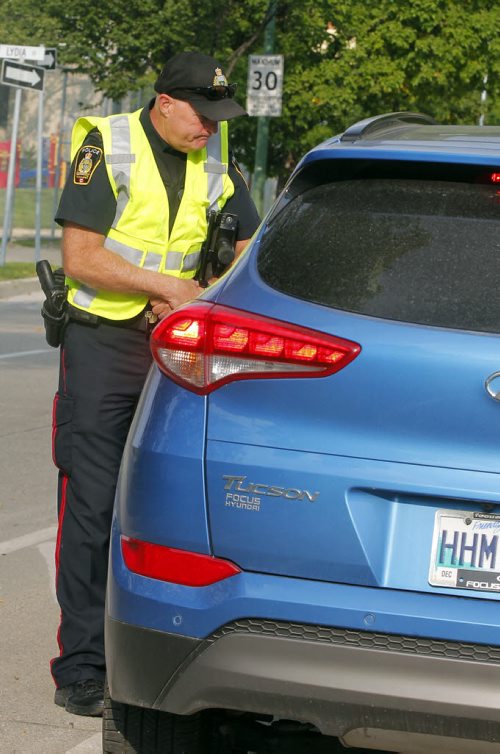 BORIS MINKEVICH / WINNIPEG FREE PRESS SCHOOL ZONE SPEED ENFORCEMENT - Const. Ray Howes enforces the 30km/hr school zone on Bannatyne Ave. near Lydia Street. The fastest car in the zone was 61km/hr  when the photog was there, and it was a teacher that was driving. Here he talks to the driver that was speeding. Sept. 1, 2016