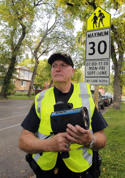BORIS MINKEVICH / WINNIPEG FREE PRESS SCHOOL ZONE SPEED ENFORCEMENT - Const. Ray Howes enforces the 30km/hr school zone on Bannatyne Ave. near Lydia Street. In this photo he poses at the sign where the zone starts. Sept. 1, 2016