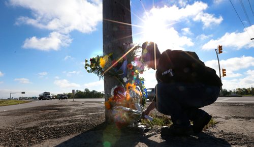 WAYNE GLOWACKI / WINNIPEG FREE PRESS
Lesley Eng places flowers at the roadside memorial at St. Anne's Road and  the Perimeter Highway for her former biology teacher Michael Slobodian, who  died Wednesday after colliding with a dump truck while on his bicycle. Sept. 8 2016