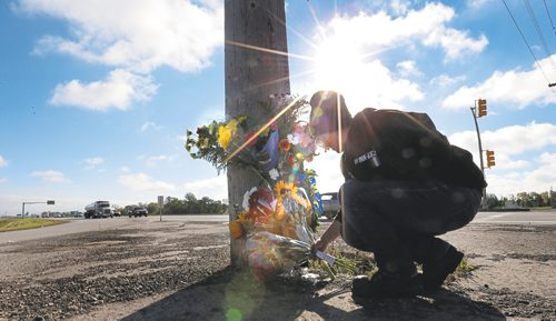 Original: WAYNE GLOWACKI / WINNIPEG FREE PRESS
Lesley Eng places flowers at the roadside memorial at St. Anne's Road and  the Perimeter Highway for her former biology teacher Michael Slobodian, who  died Wednesday after colliding with a dump truck while on his bicycle. Sept. 8 2016 Published: WAYNE GLOWACKI / WINNIPEG FREE PRESS
