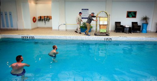 PHIL HOSSACK / WINNIPEG FREE PRESS -   Max Kirouac and his cousin Chris Kirouac of the Bee Project wheel beehives through the pool area past curious swimmers at the Fairmont Hotel Tuesday evening. See Wendy King's story.  September 13, 2016