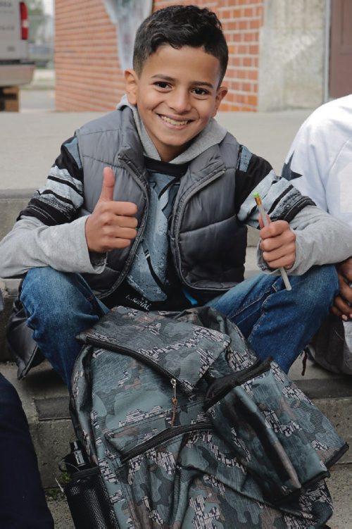 Canstar Community News High John School newcomer student smiles after he receives new backback filled with school tools donated by Tools for School on Sept. 13, 2016. (Ligia Braidotti/Canstar Community News)
