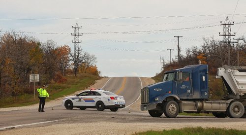 MIKE DEAL / WINNIPEG FREE PRESS

An RCMP officer directs traffic on Hwy 213 (Garven Road) at the intersection with Hwy 207. The driver of a pickup truck was in a head on collision with a gravel truck Monday morning. 

161003
Monday, October 03, 2016