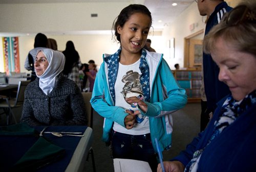 MIKE DEAL / WINNIPEG FREE PRESS
Aya, 10, translates for her parents during an interview at a potluck supper hosted by Refuge Winnipeg for the three Syrian refugee families who arrived here last October and all the people who privately sponsored them Monday afternoon at the First Unitarian Universalist Church of Winnipeg.
161010 - Monday, October 10, 2016 - 

