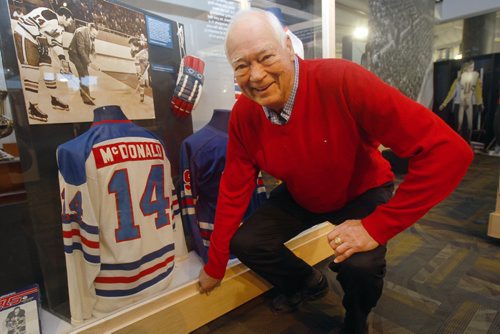 JOE BRYKSA / WINNIPEG FREE PRESS 80 year old Left-winger hockey legend Ab McDonald  at the Manitoba Sports Hall of Fame- he kneels in front of the exhibit that includes his jersey- 1 of 16 cases in the 60 Years of Pro Hockey exhibit that will be on display until Apr 2017-    -Oct 13, 2016 -(See Scotts story)
