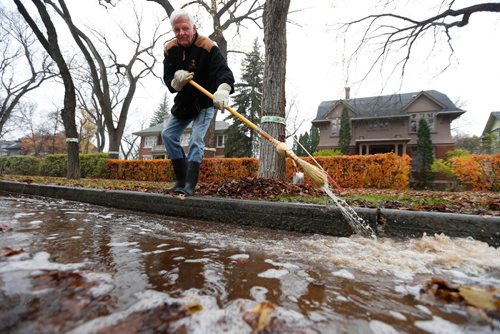 WAYNE GLOWACKI / WINNIPEG FREE PRESS


 Robert Young in front of his home on Yale Ave. moves water and leaves towards a drain. The water collects in a dip in the street and  has been a problem all summer and now has the leaves in it. Alex Paul story.   story Oct. 28 2016