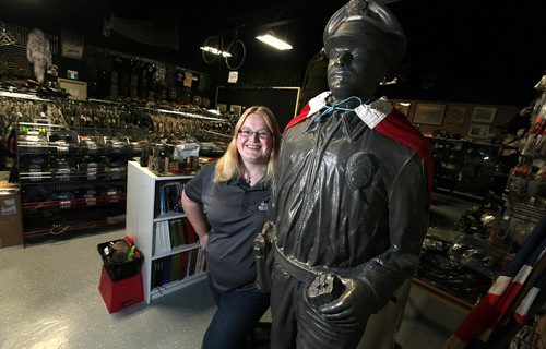 PHIL HOSSACK / WINNIPEG FREE PRESS - Marway Militaria, specializes in military memorabilia See Bill Redekop's tale. Jaime Cline poses beside "The Dude" a concrete statue of an American Police Officer that welcomes visitors to the shop as they enter the door. November 8, 2016
