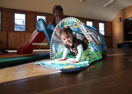 
RUTH BONNEVILLE / WINNIPEG FREE PRESS

Faith Page: Story: Harrow United Church celebrates a century of helping their neighbourhood with community programs.
17-month-old Mara Daniels plays in tunnel at playtime program for grandkids with  grandparents.  Grandmother Susan Ketchen behind her.  
November 10, 2016