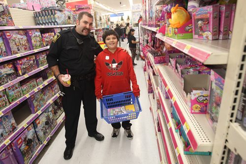 JOE BRYKSA / WINNIPEG FREE PRESS Cst. Devon Hurst  at Walmart with Aiden Campbell from David Livingston School at the Winnipeg Police Service 10th Annual Winnipeg COPSHOP event at St Vital Centre- COPSHOP gives students a unforgettable day of shopping with a police officer- Students are selected for the day  by need, specific academic or sporting achievements and volunteerism. Students are picked up at their schools by police officers and taken to St. Vital Centre, where they will be given $200 dollars to enjoy a two hour Christmas shopping spree. - Nov 23, 2016 -( Standup photo)