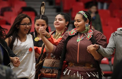 
RUTH BONNEVILLE / WINNIPEG FREE PRESS

Jingle dress dancers Autumn Monkman (right) , Iroc Levasseur (centre) and Ainsley Clarke lead members of the audience watching the Canada West Basketball Tournament at the U of W into a round dance during halftime Thursday evening.  The women and mens U of W Wesman teams were playing the Brandon University Bobcats.  
Standup 2
November 24, 2016