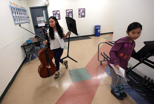 PHIL HOSSACK / WINNIPEG FREE PRESS - (left) Cheyanne Sutherland  and Ehrica Demillo right, head to rehearsal with music stands. Young musicians head to rehearsal, Students from King Edward School  are involved in the WSOs Sistema program, which aims to connect youth in undeserved areas with the pursuit of excellence in music education, spent the afternoon and evening practicing for an upcoming concert. See Melissa Martin's story. December 1, 2016