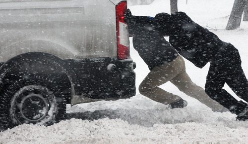 JOE BRYKSA / WINNIPEG FREE PRESS Cameron Batista , front, and others help to push out a delivery van stuck in snow on Ellice Ave in Winnipeg  The city and southern Manitoba will have winter storm/ blizzard conditions for the day-  Dec 06, 2016 -( standup Photo)