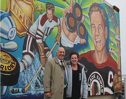 Canstar Community News Take Pride Winnipeg! executive director Tom Ethans and artist Jennifer Mosieno stand in front of the new Billy Mosienko mural on Nov. 28, 2016.