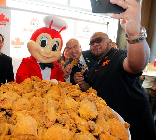 BORIS MINKEVICH / WINNIPEG FREE PRESS
Jollibee Foods Corporation (JFC), the worlds 9th largest restaurant company, brings an early Christmas gift to Canadians as it opens its first-ever store in the country on Ellice Ave. in Winnipeg tomorrow. L-R Jollibee mascot, MB MLA for St. Norbert Jon Reyes  and JP Sumbillo (taking selfie) with massive bucket of chicken during the celebrations. REBECCA DAHL STORY  Dec. 14, 2016