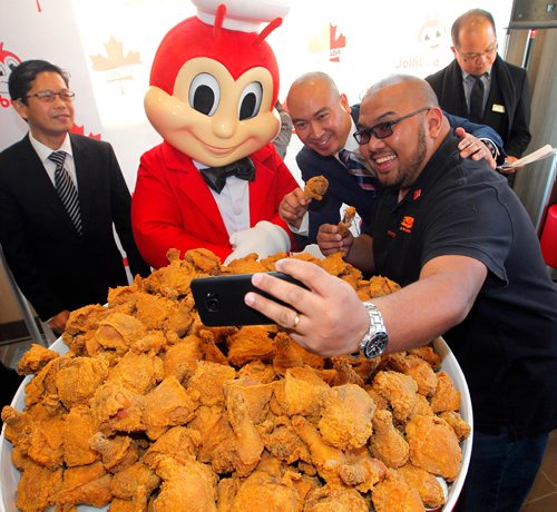 BORIS MINKEVICH / WINNIPEG FREE PRESS
Jollibee Foods Corporation (JFC), the worlds 9th largest restaurant company, brings an early Christmas gift to Canadians as it opens its first-ever store in the country on Ellice Ave. in Winnipeg tomorrow. L-R Philippine Honorary Consul (Winnipeg, Canada) Ronaldo Opina, Jollibee mascot, MB MLA for St. Norbert Jon Reyes, and JP Sumbillo enjoy a selfie with massive bucket of chicken during the celebrations. REBECCA DAHL STORY  Dec. 14, 2016