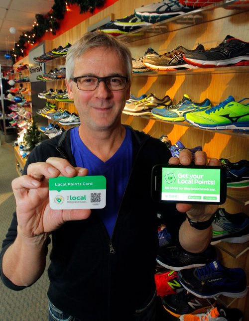 BORIS MINKEVICH / WINNIPEG FREE PRESS
BIZ - Erick Oland is the owner of City Park Runners. His business participates in a buy-local rewards program called The Local Frequency. Shoppers can collect points at participating retailers and redeem that any other participating retailers. Here he holds the customer card, left, and the retailers card scanner, right, in his shoe store. MARTIN CASH STORY. Dec. 16, 2016