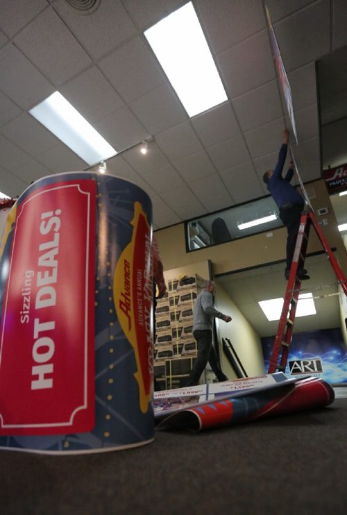 TREVOR HAGAN / WINNIPEG FREE PRESS
Reg Bergmann hangs banners advertising Advance's boxing week sales known as the Krazy Karnival, Saturday, December 24, 2016.