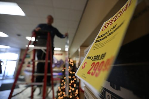 TREVOR HAGAN / WINNIPEG FREE PRESS
Reg Bergmann hangs banners advertising Advance's boxing week sales known as the Krazy Karnival, Saturday, December 24, 2016.