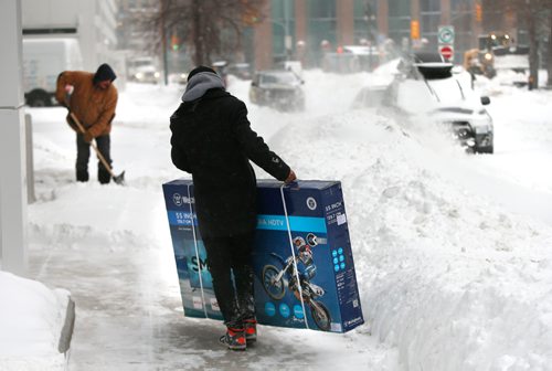 WAYNE GLOWACKI / WINNIPEG FREE PRESS

Gagandeep Singh arrives home with his Boxing Day TV purchase as Gilles Laramee clears the sidewalk in front of the Colony Commons during the snow storm Monday. Dec.26 2016