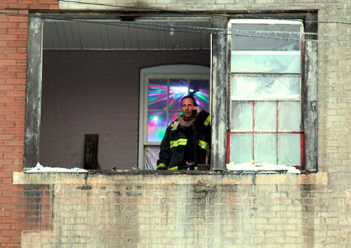 BORIS MINKEVICH / WINNIPEG FREE PRESS
A firefighter looks out the window of a third floor apartment in the rear of 181 Balmoral Street. A fire broke out in the apartment this afternoon. Photo taken after fire was out and the last crew was packing up.  JAN. 12, 2017
