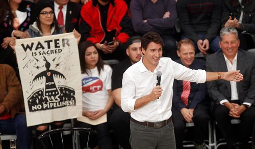 PHIL HOSSACK / WINNIPEG FREE PRESS -  Prime Minister Justin Trudeau debates hecklers in the Town Hall crowd at the University of Winnipeg Thursday as people seated behind him unfurl banners. See story.  ....January 26, 2017